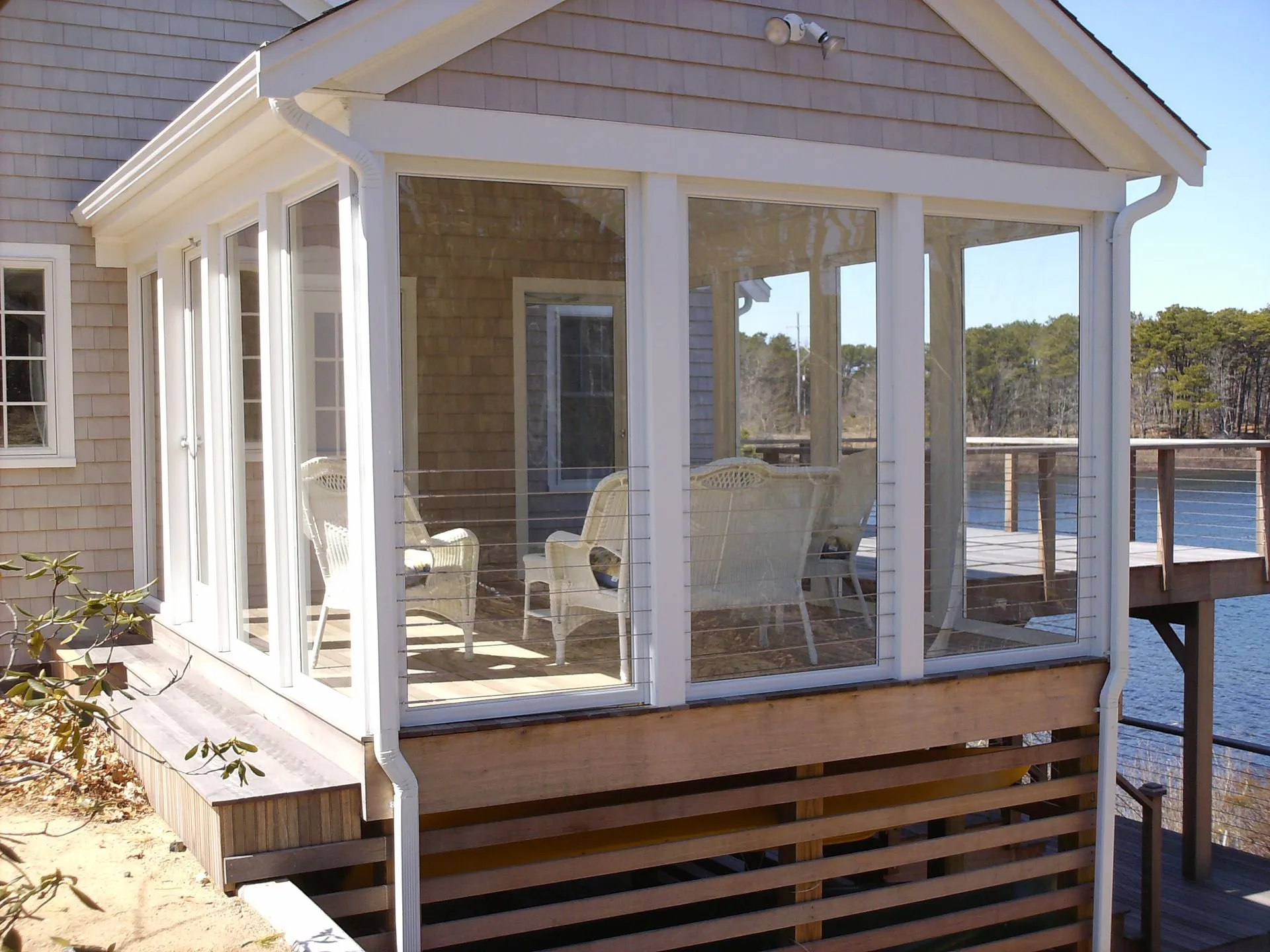 a house with a screened in porch overlooking a body of water