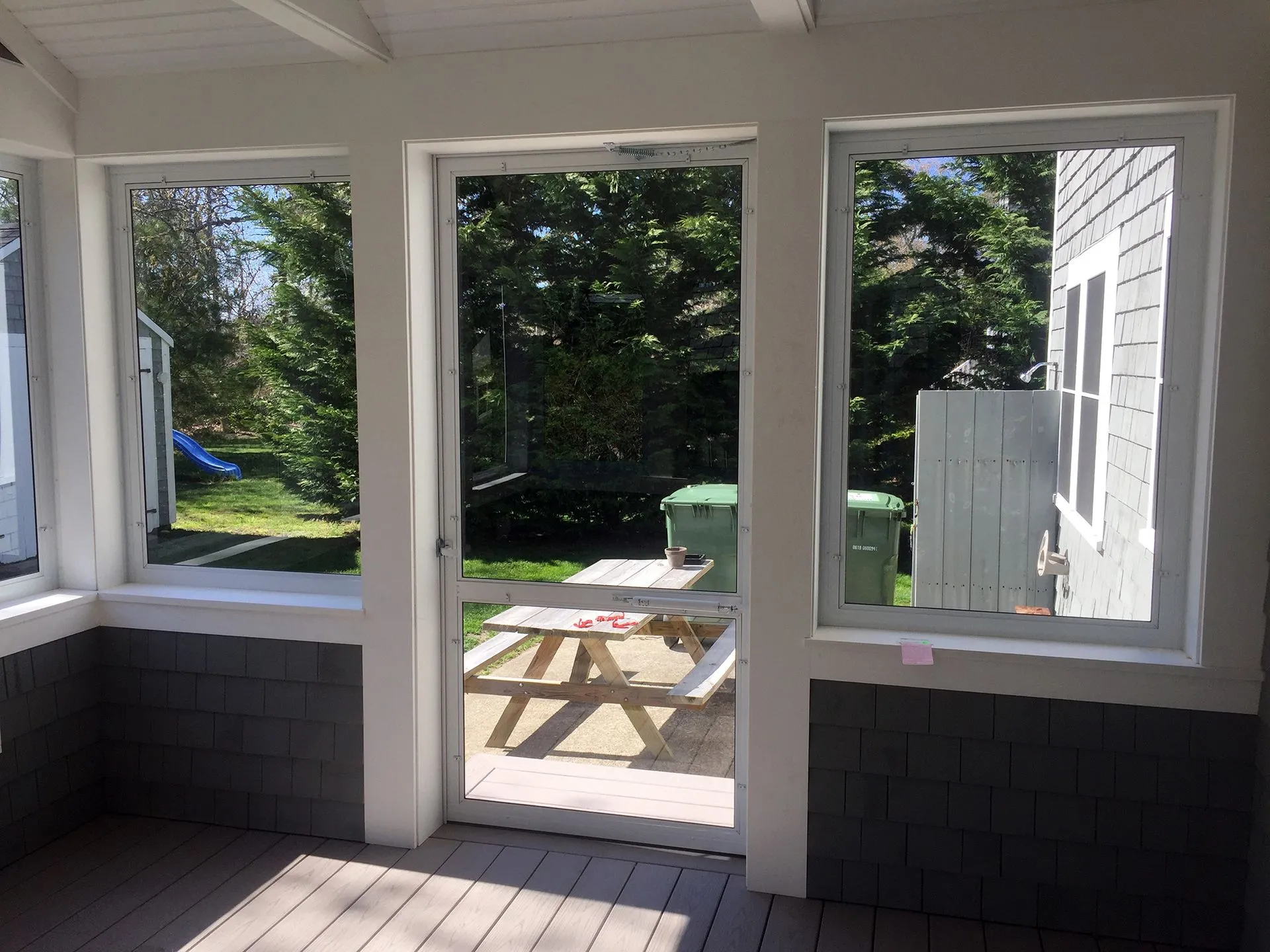 a porch with a picnic table and trees in the background