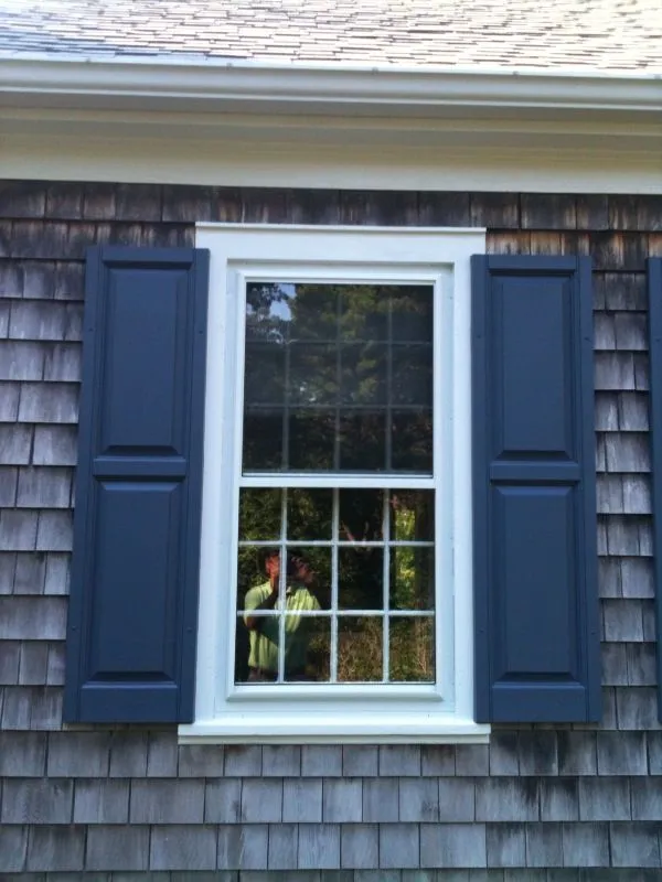 a window with blue shutters on the side of a house