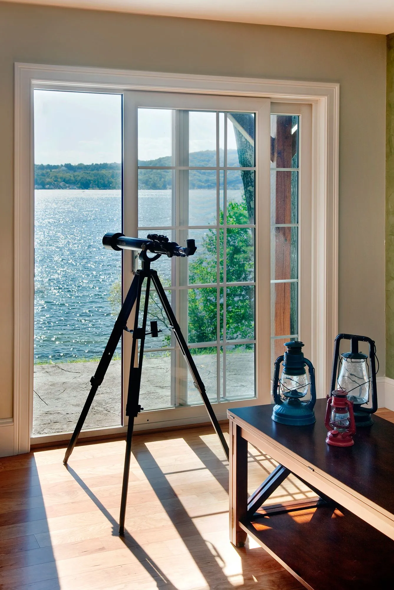 a telescope is sitting on a tripod in front of a window overlooking a lake