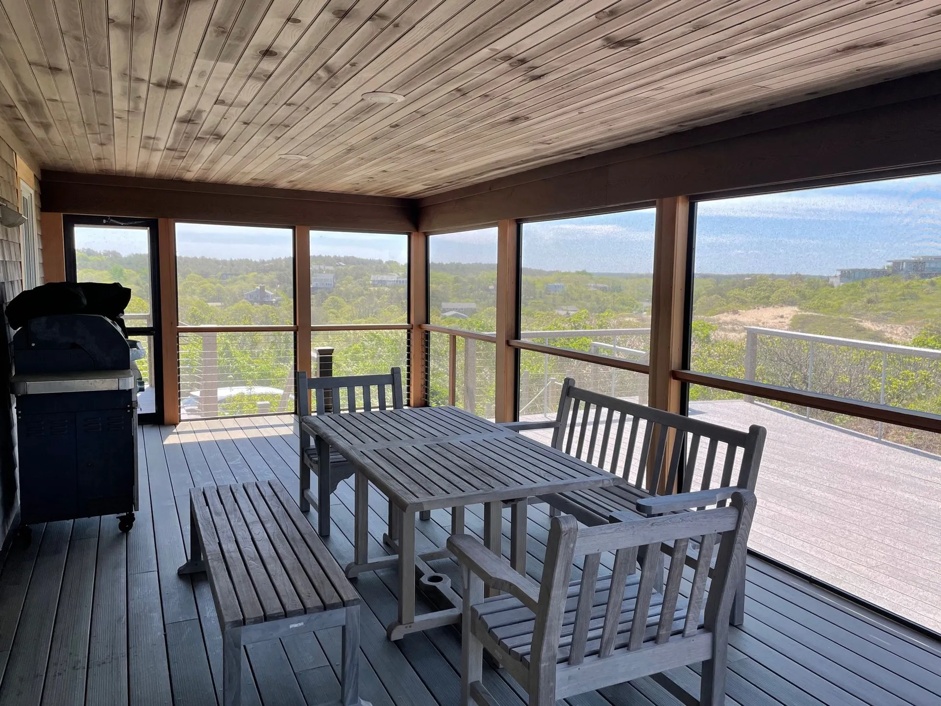 a screened in porch with a table and chairs and a grill