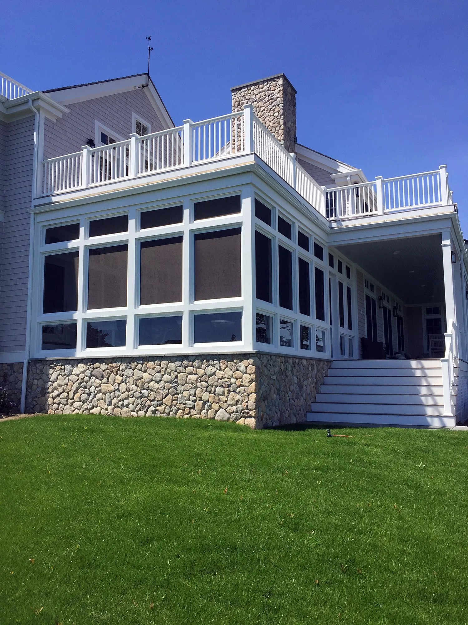 the back of a large house with a screened in porch and stairs