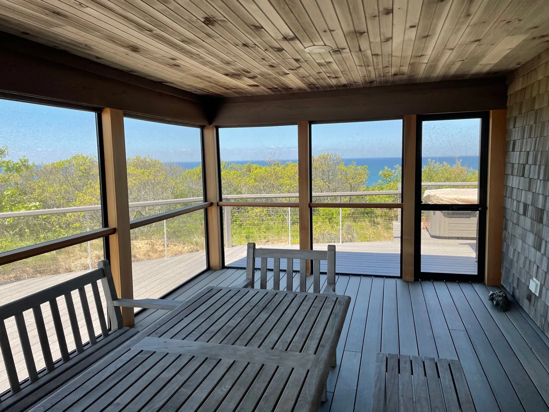 a screened in porch with a table and chairs and a view of the ocean