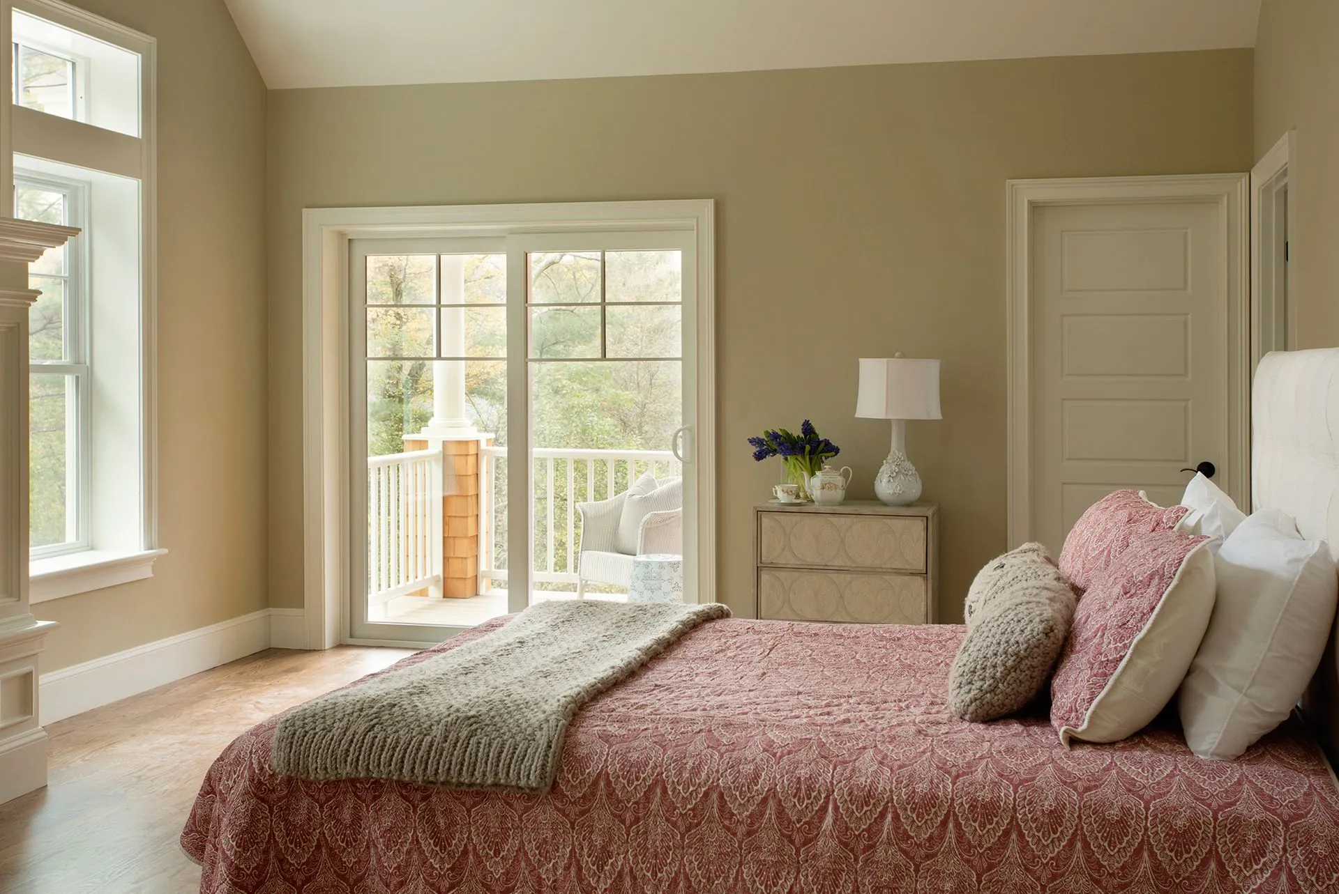a bedroom with a bed, nightstand, lamp and sliding glass doors leading to a balcony