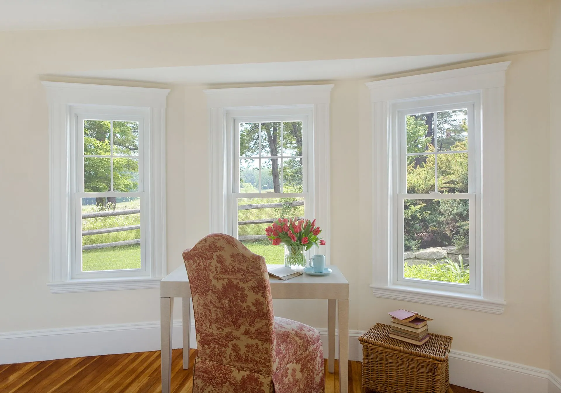 a room with two windows and a desk with a vase of flowers on it