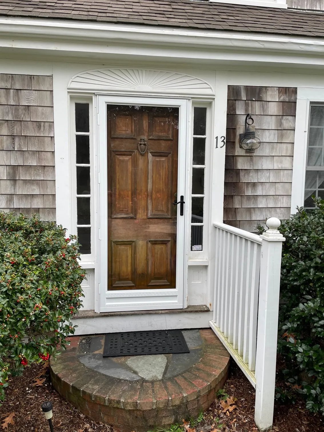 the front door of a house with a screen door and a white railing