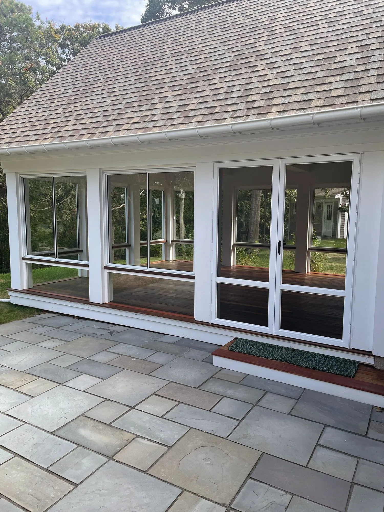 a white house with a screened in porch and sliding glass doors