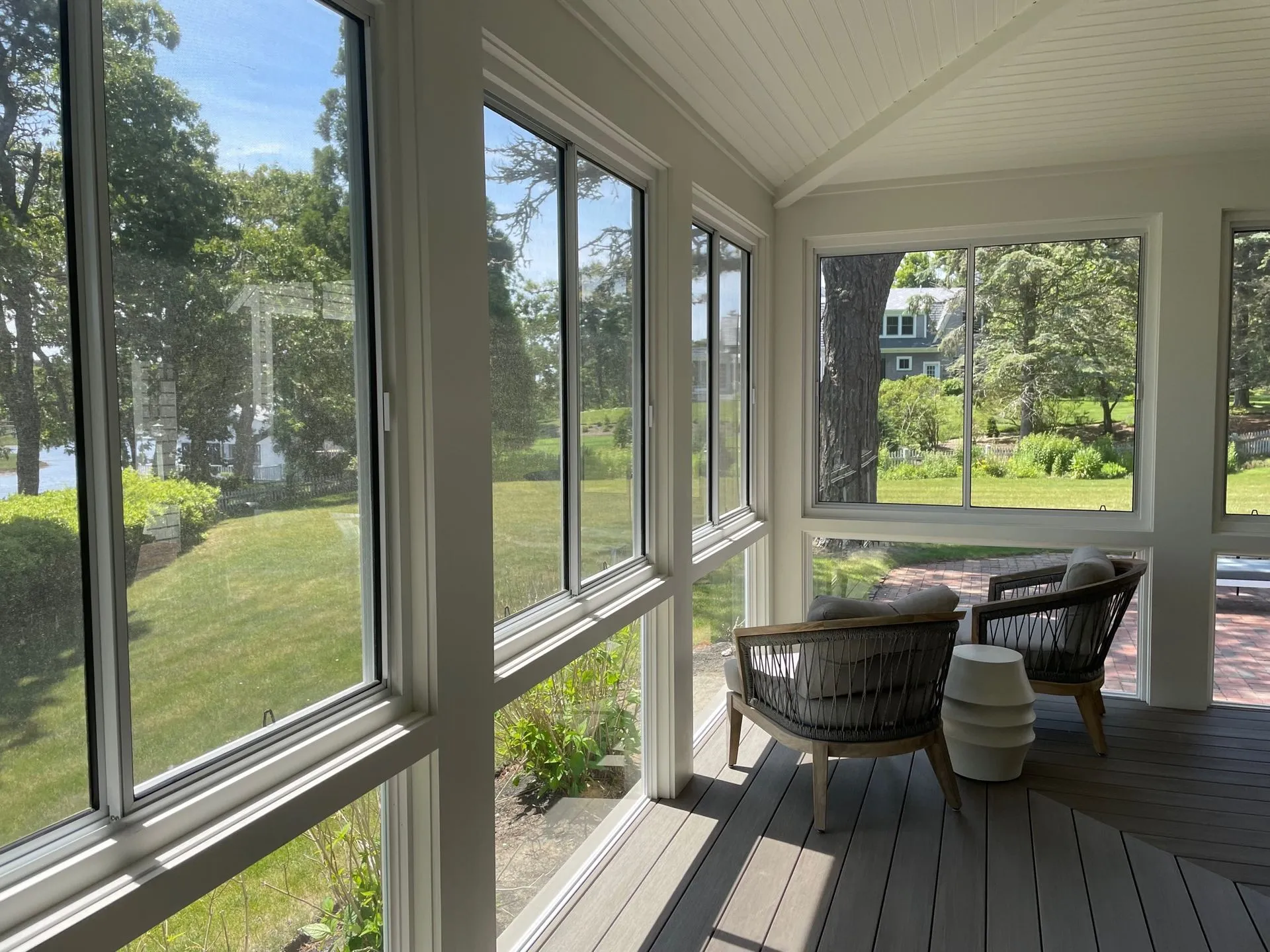 a screened in porch with a lot of windows and chairs