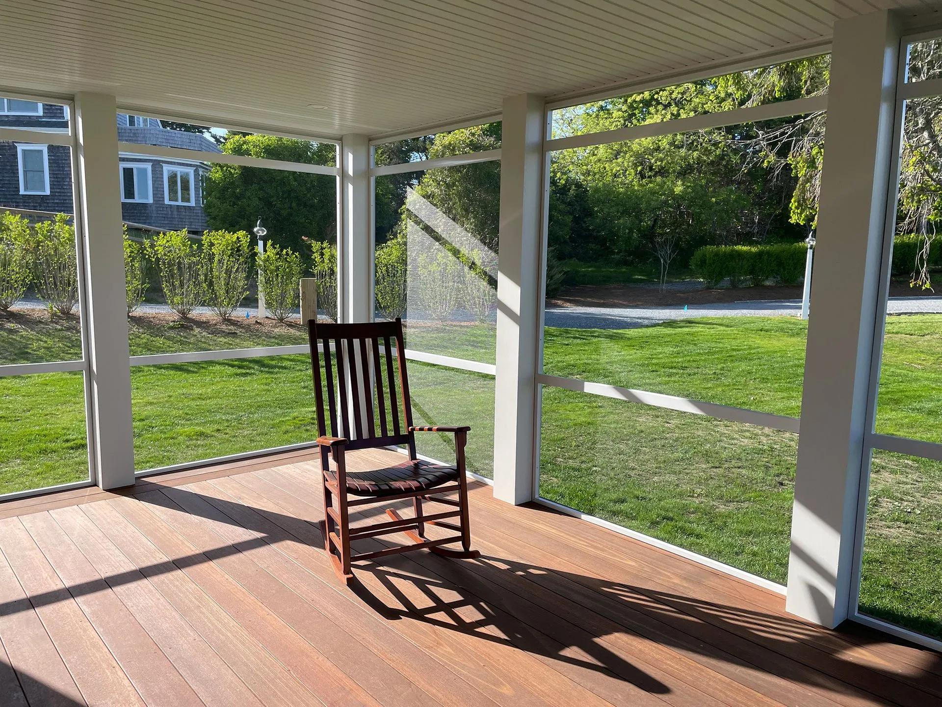 a rocking chair is sitting on a screened in porch