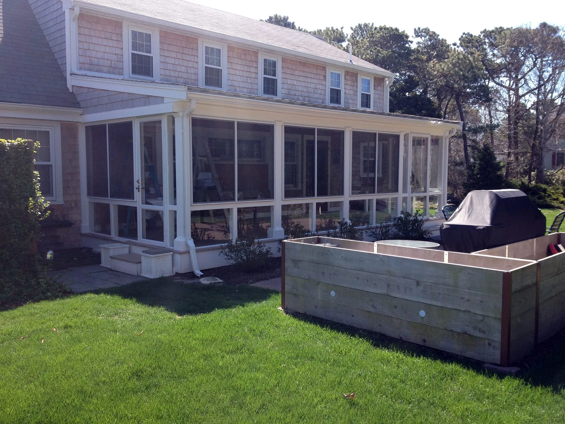 a house with a screened in porch and a grill