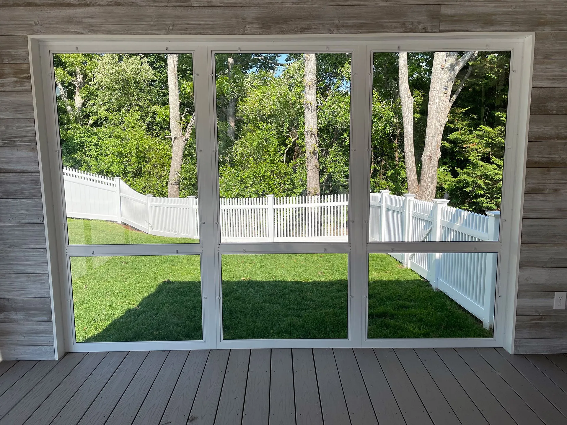 a screened in porch with a view of a fence and trees